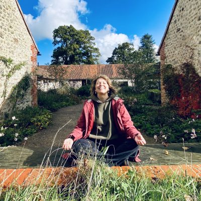 Crosslegged Anu laughing in Wraxal