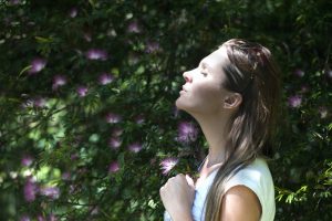 Woman with eyes closed, enjoying a state of wellbeing in nature
