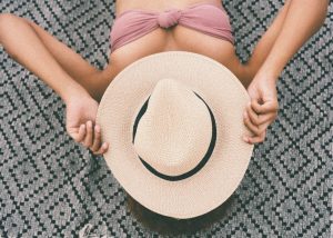 Woman protecting her face with a hat whilst sunbathing