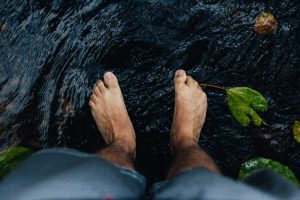 Man feeling his feet in water with waterlily leaves